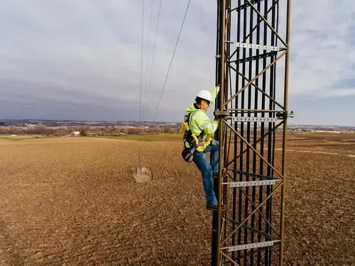 worker climbing tower with fall protection