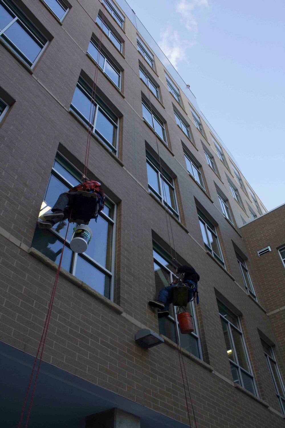 window cleaners suspended from an anchor